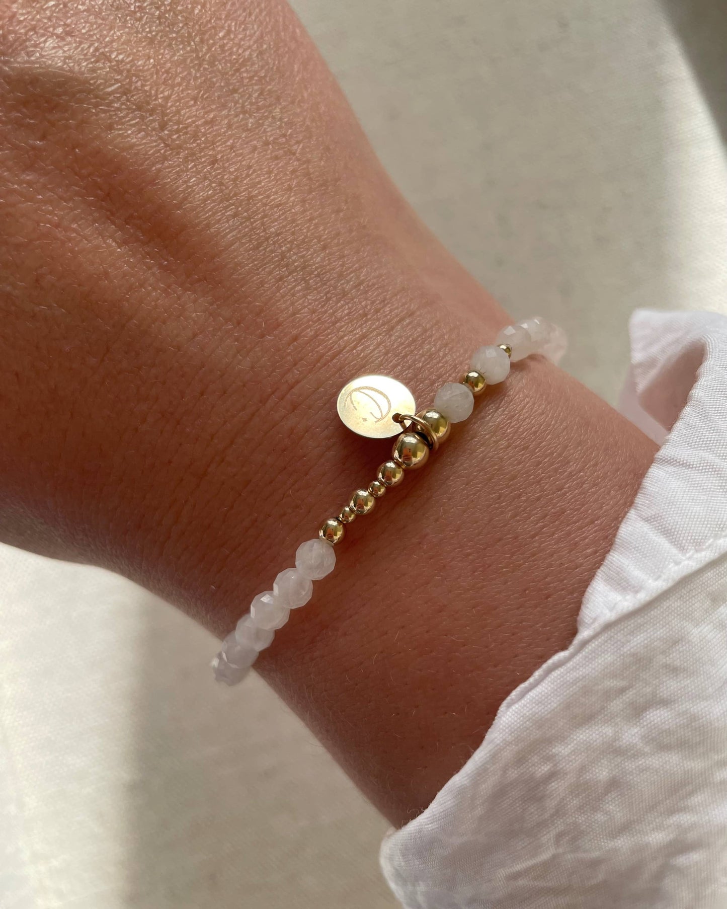 Moonstone Stretch Bracelet shown on a wrist. A dainty and modern moonstone stretch bracelet for June Birthdays. Celestial Star and Moon charm.